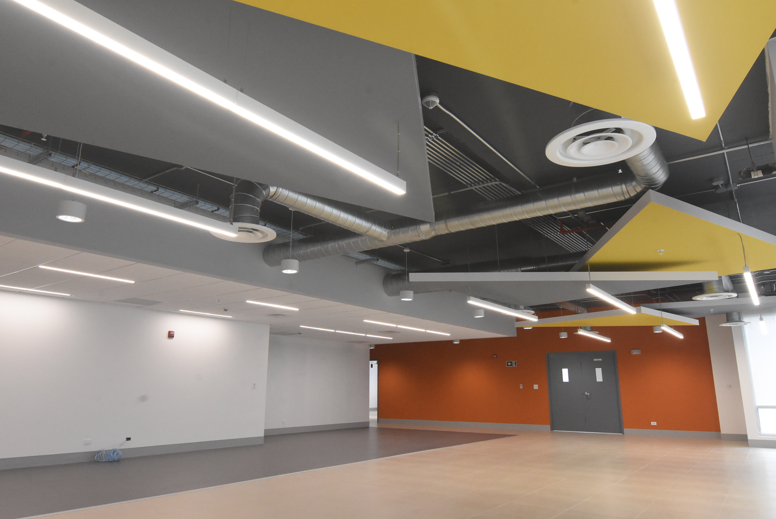 Oficinas Caterpillar: cielo geométrico amarillo y gris, iluminación e instalaciones integradas
